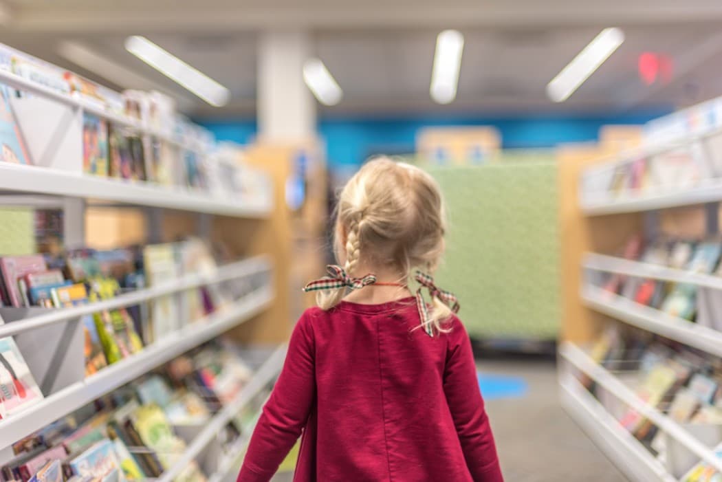 Little girl searching the library for a book about the dentist